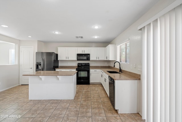 kitchen featuring a kitchen breakfast bar, sink, black appliances, a center island, and white cabinetry