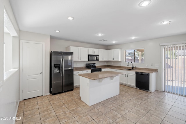 kitchen with a center island, black appliances, sink, white cabinetry, and a breakfast bar area