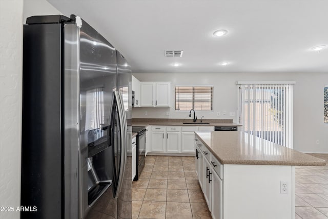 kitchen with stainless steel appliances, sink, light tile patterned floors, white cabinets, and a kitchen island