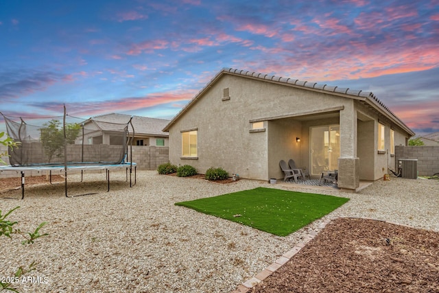 17573 W Via De Luna Dr, Surprise, AZ 85387 - back of house featuring a trampoline, central AC unit, stucco siding, a fenced backyard, and a patio