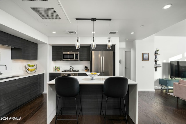 kitchen with a kitchen breakfast bar, hanging light fixtures, dark wood-type flooring, and appliances with stainless steel finishes