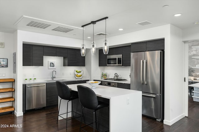 kitchen featuring pendant lighting, a center island, dark wood-type flooring, sink, and appliances with stainless steel finishes