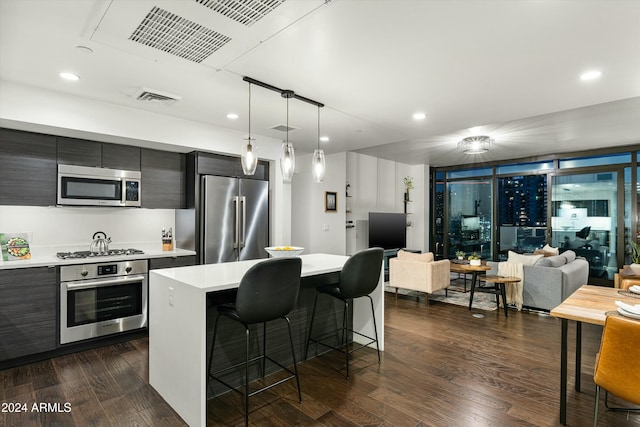 kitchen with a center island, dark hardwood / wood-style flooring, pendant lighting, a breakfast bar, and appliances with stainless steel finishes