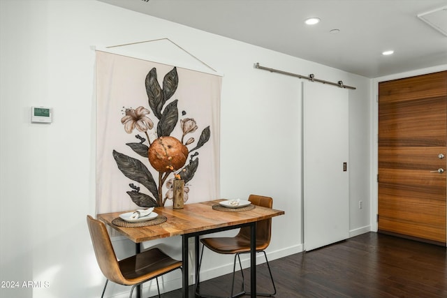 dining space with a barn door and dark hardwood / wood-style flooring