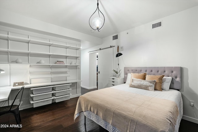 bedroom with a barn door and dark wood-type flooring