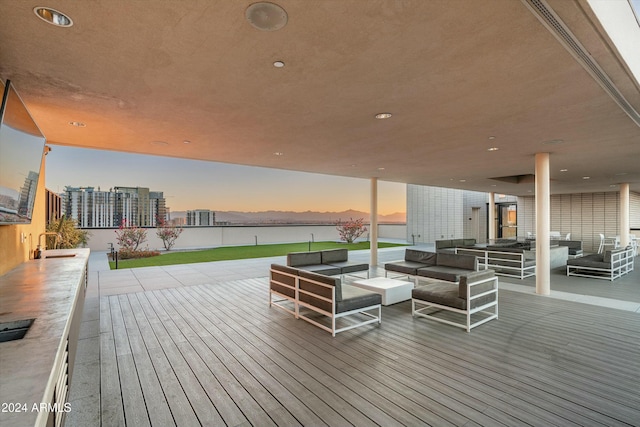 deck at dusk featuring an outdoor living space, a water view, and sink