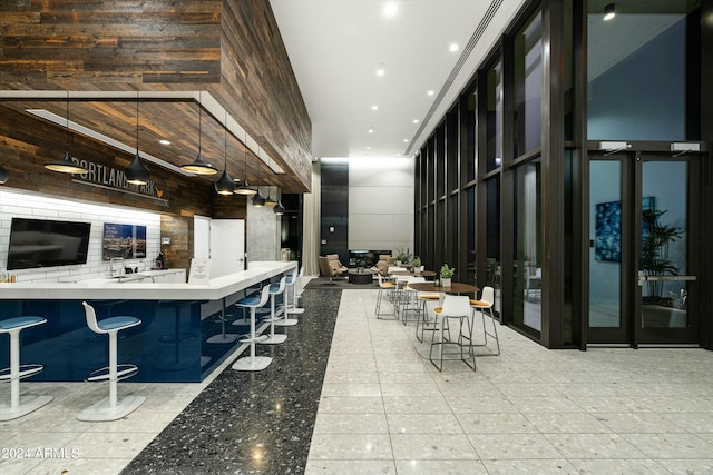 bar with hanging light fixtures and a high ceiling