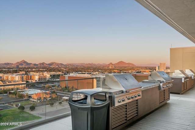 patio terrace at dusk featuring a grill, a mountain view, and a balcony