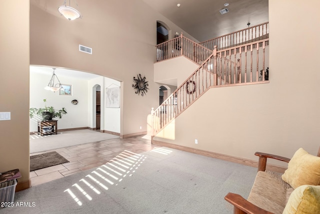 carpeted entryway featuring a towering ceiling