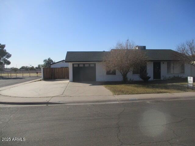 ranch-style home featuring a garage, fence, and concrete driveway