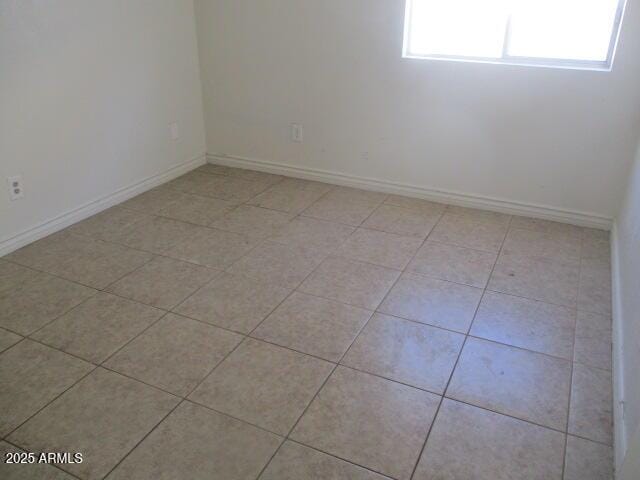 spare room featuring baseboards and light tile patterned floors