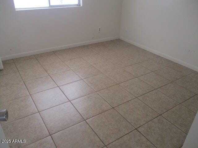 unfurnished room with light tile patterned floors and baseboards