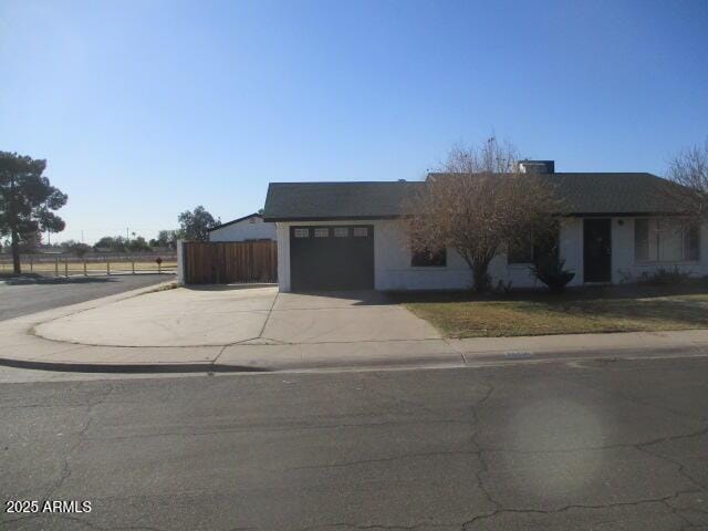 view of front facade featuring driveway, a garage, and fence