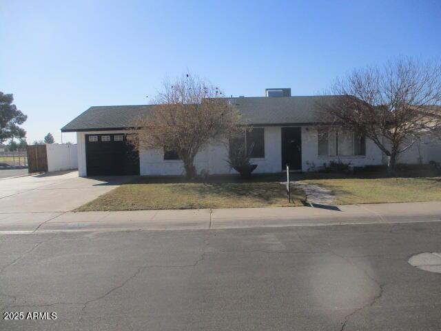 single story home featuring a garage, concrete driveway, fence, and a front lawn