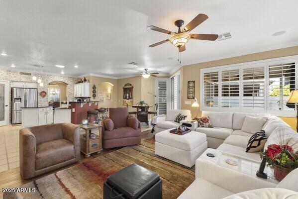 tiled living room with ornamental molding and ceiling fan