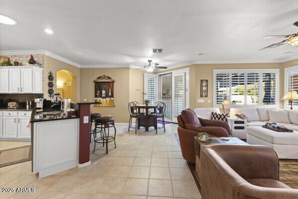 tiled living room featuring sink, ornamental molding, and ceiling fan