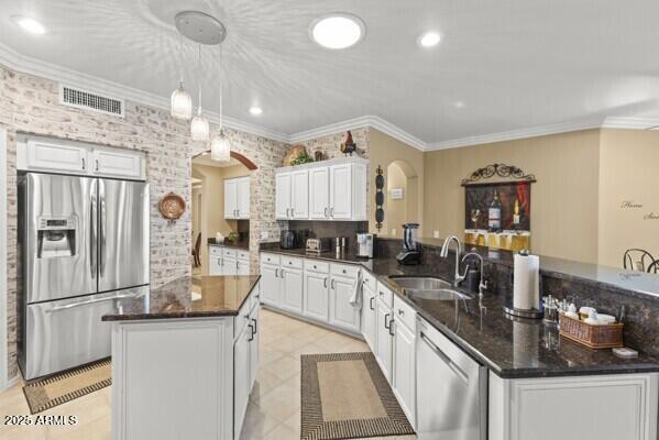 kitchen with a kitchen island, decorative light fixtures, white cabinetry, sink, and stainless steel appliances