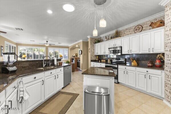 kitchen with sink, white cabinetry, ornamental molding, a kitchen island, and stainless steel appliances