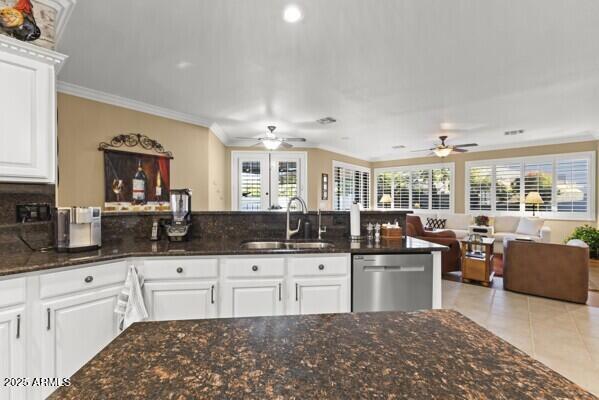 kitchen featuring sink, crown molding, light tile patterned floors, white cabinets, and stainless steel dishwasher