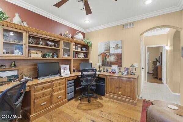 office area featuring crown molding, built in desk, ceiling fan, and light hardwood / wood-style flooring