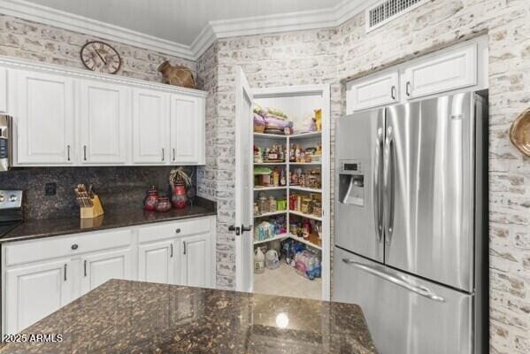 kitchen featuring dark stone countertops, ornamental molding, white cabinets, and appliances with stainless steel finishes