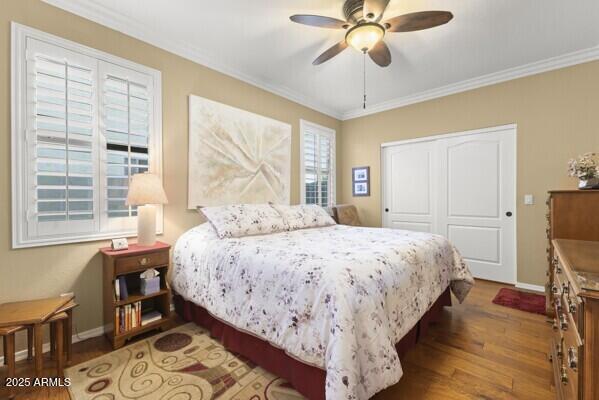 bedroom with hardwood / wood-style flooring, ceiling fan, crown molding, and a closet