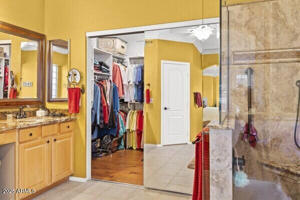 bathroom with vanity, crown molding, tile patterned floors, and tiled shower