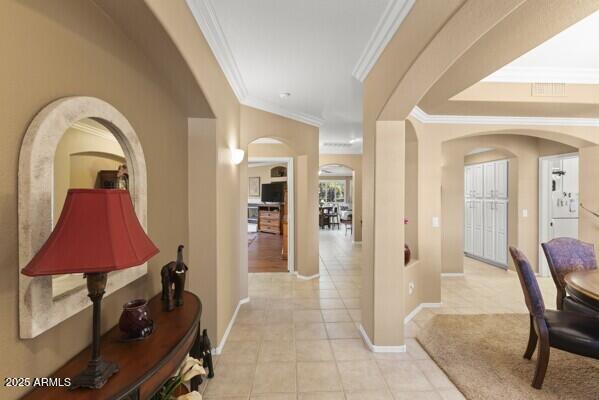 hallway featuring light tile patterned floors and crown molding