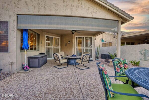 patio terrace at dusk featuring ceiling fan and an outdoor fire pit