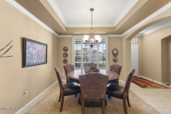 dining area featuring a raised ceiling, ornamental molding, and a notable chandelier