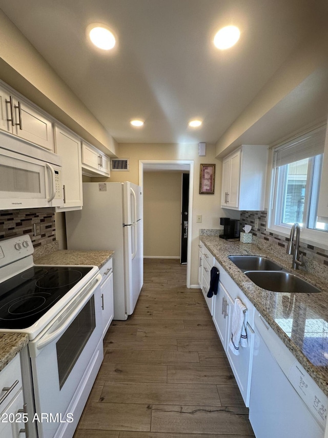 kitchen with dark hardwood / wood-style flooring, sink, white cabinets, and white appliances