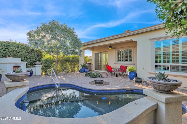 view of pool featuring a hot tub, ceiling fan, a patio, and exterior fireplace