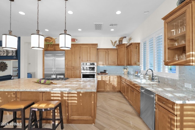 kitchen featuring light stone countertops, a center island, stainless steel appliances, and sink