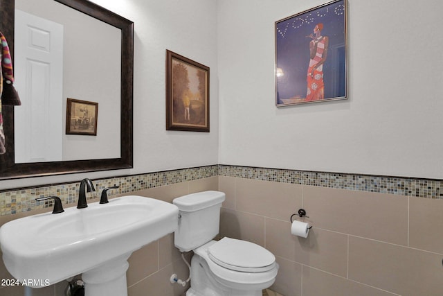 bathroom featuring toilet, sink, and tile walls