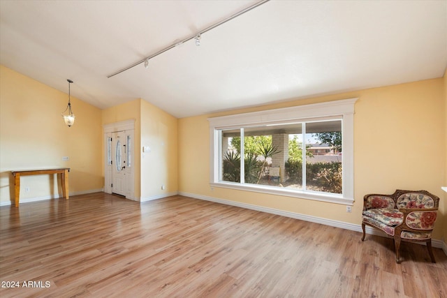 interior space with track lighting, lofted ceiling, and light hardwood / wood-style flooring