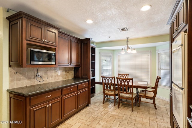 kitchen featuring hanging light fixtures, backsplash, a wealth of natural light, and a notable chandelier