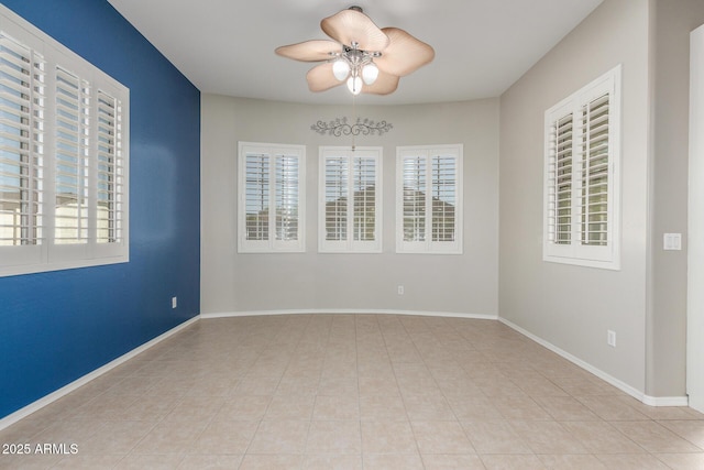 tiled empty room with baseboards and ceiling fan