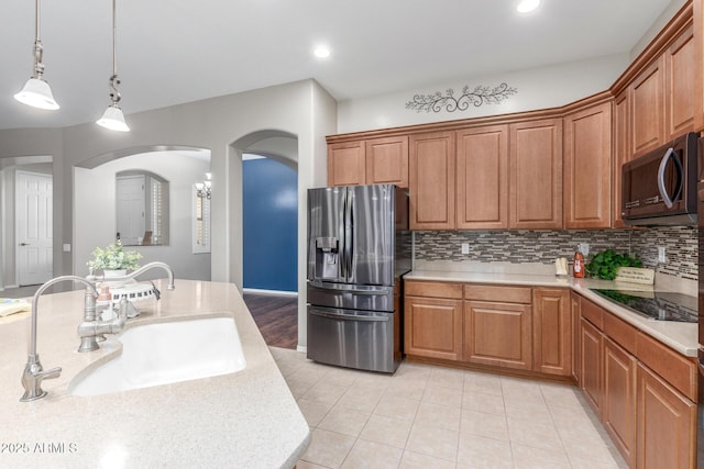 kitchen with pendant lighting, a sink, stainless steel fridge, black electric cooktop, and backsplash