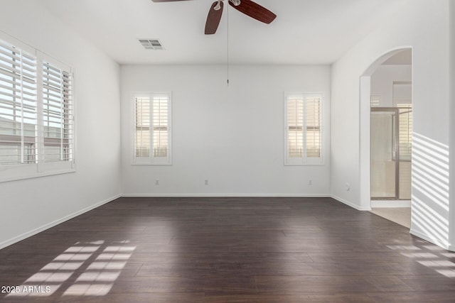spare room featuring arched walkways, visible vents, wood finished floors, and ceiling fan