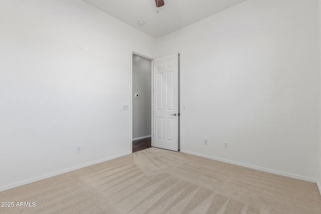 empty room featuring light carpet, baseboards, and a ceiling fan