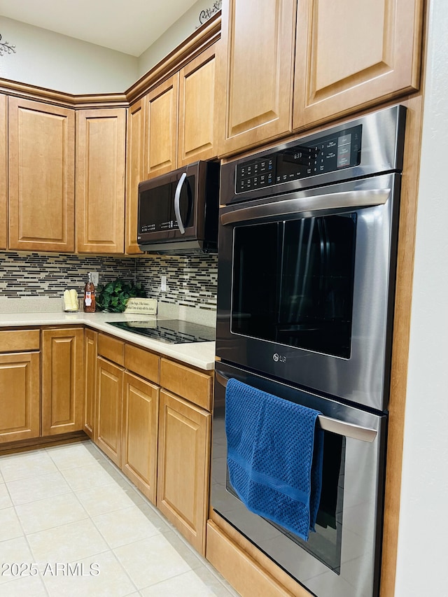 kitchen featuring tasteful backsplash, double oven, light countertops, and black electric stovetop