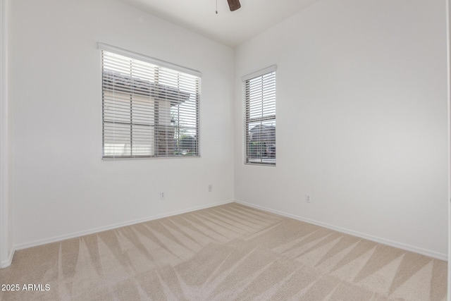 empty room featuring light colored carpet, baseboards, and ceiling fan