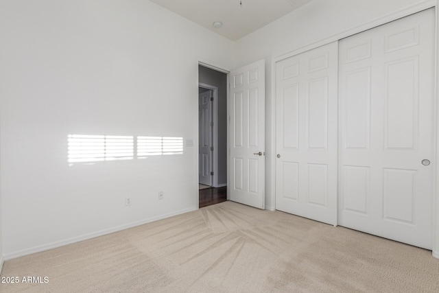unfurnished bedroom with carpet, a closet, and baseboards