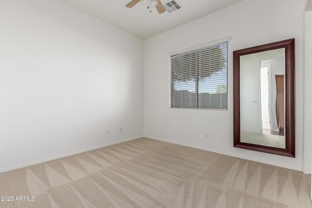 empty room with baseboards, light colored carpet, ceiling fan, and visible vents