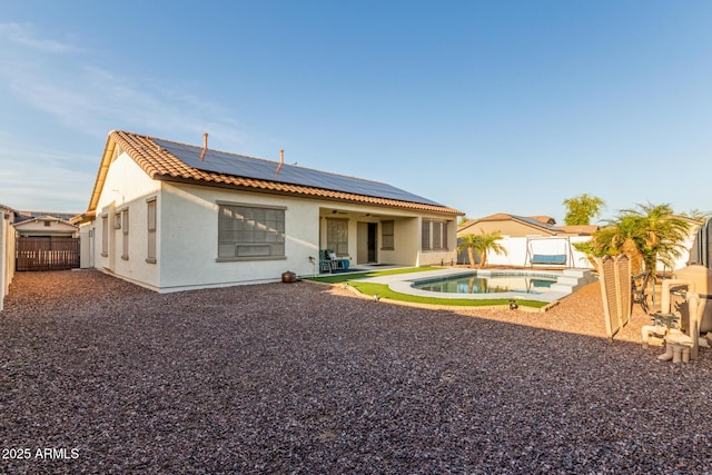 back of property with solar panels, a tiled roof, a fenced backyard, a patio, and stucco siding