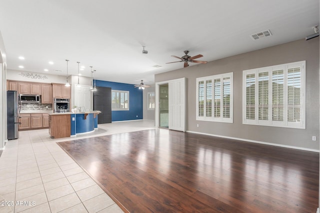 unfurnished living room with visible vents, light tile patterned floors, baseboards, a ceiling fan, and recessed lighting