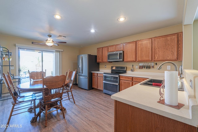 kitchen with ceiling fan, sink, appliances with stainless steel finishes, and light hardwood / wood-style flooring