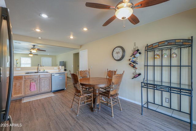 dining space with ceiling fan, wood-type flooring, and sink