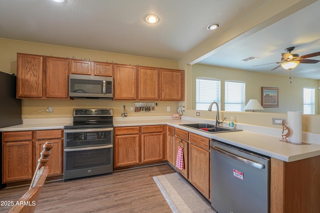 kitchen with a wealth of natural light, sink, stainless steel appliances, and light hardwood / wood-style floors