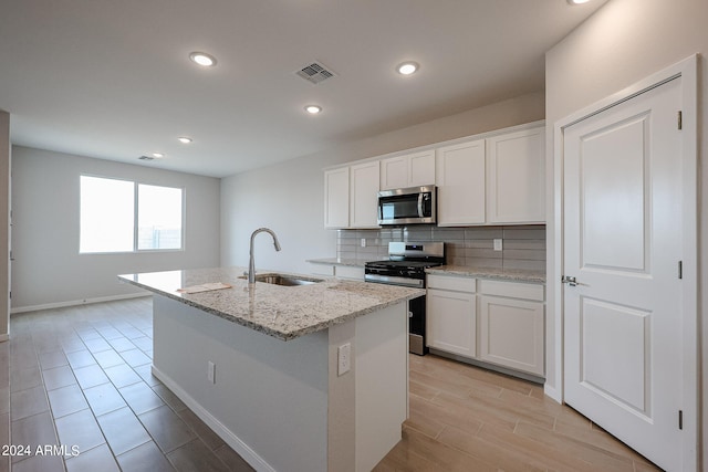 kitchen featuring a center island with sink, sink, appliances with stainless steel finishes, and white cabinetry